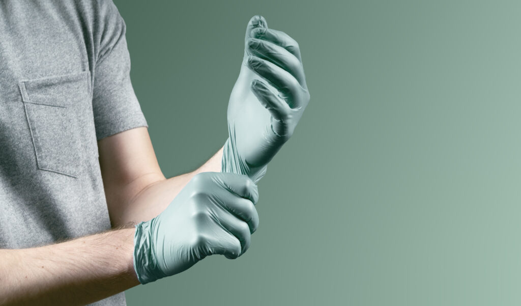 Person zieht Nitril-Einmalhandschuh an