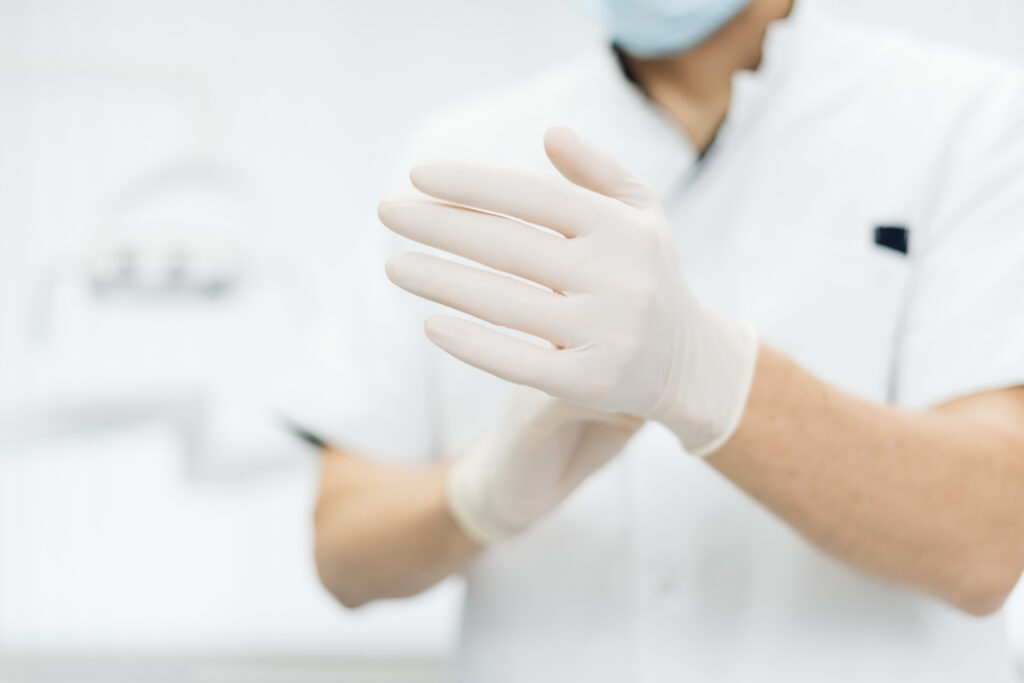 Nahaufnahme von Arzthänden mit weißen Einmalhandschuhen
